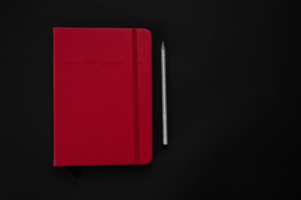 Czerwony planer bullet journal i ołówek na czarnej powierzch